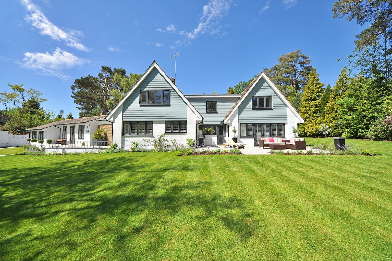 White-painted Texas home with healthy lawn and well-kept shade trees at the curb.